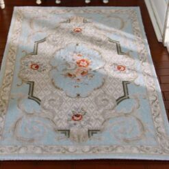 Victorian miniature rug with a floral medallion, soft blue background, and scrolls.