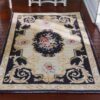 Black Victorian miniature rug with floral medallion and roses in pink and cream.