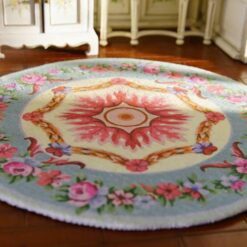 Miniature Victorian-style rug with a floral wreath and rose medallion design in soft colors.
