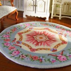 A Victorian-style miniature rug with a central rose wreath medallion surrounded by floral details.