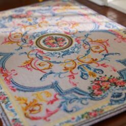 Pastel-colored miniature rug with floral accents and a central floral medallion design.