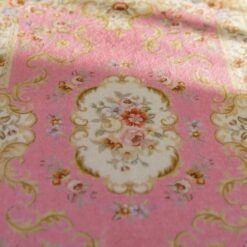 Victorian-style miniature rug in soft pink with floral accents and medallion design.