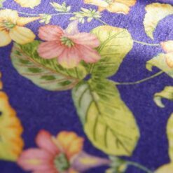 A miniature rug featuring colorful tropical flowers against a blue background with lush green leaves