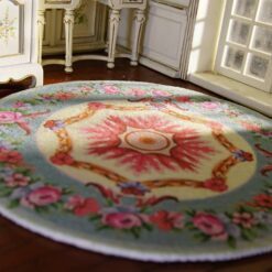 A Victorian-style miniature rug with a central rose wreath medallion surrounded by floral details.
