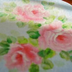 A Victorian-style round rug featuring a rose wreath medallion with pink roses and floral accents.