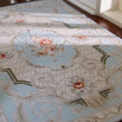 Victorian miniature rug with a floral medallion, soft blue background, and scrolls.