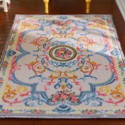 Pastel-colored miniature rug with floral accents and a central floral medallion design.
