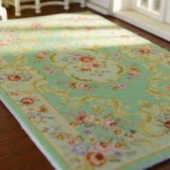 Miniature Victorian rug in soft green with floral patterns and medallion detail.