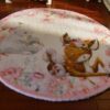 A soft, pastel-colored miniature rug featuring a deer and baby rabbits surrounded by flowers.