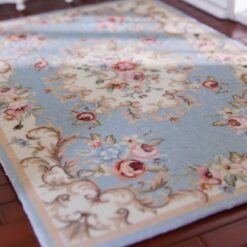 Blue miniature rug with vintage floral patterns in pink, cream, and green.