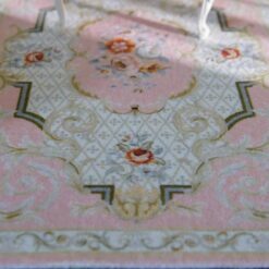 Pink Victorian miniature rug with floral medallion and scroll detailing.