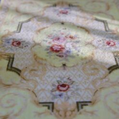 Light yellow Victorian miniature rug with floral medallion and intricate scroll designs.