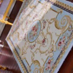 Victorian miniature rug with floral scrolls, roses, and a central medallion in soft pastel colors.