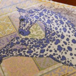 Miniature rug with a running horse design in purple, yellow, and pink tones with intricate detailing.