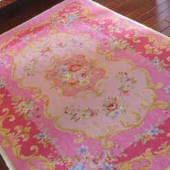 Victorian style miniature rug in pink with floral designs and golden scrollwork