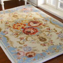 French Aubusson-style miniature rug with a light blue background, floral bunches, and a cream-colored floral medallion.