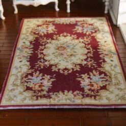 Victorian-style miniature rug in burgundy, with floral medallion and intricate scroll patterns.
