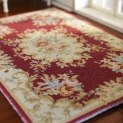 Victorian-style miniature rug in burgundy, with floral medallion and intricate scroll patterns.