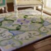 Pastel green miniature rug with swirls, vines, and floral accents, perfect for modern dollhouse interiors.