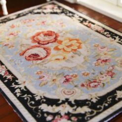 Persian-inspired miniature rug with a black background, floral bouquet center, and intricate floral border.
