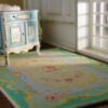 French Aubusson-style miniature rug with floral motifs and delicate scrollwork in blue and green hues.