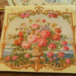 Golden urn filled with roses and flowers set against an ocean backdrop, a miniature Aubusson tapestry.