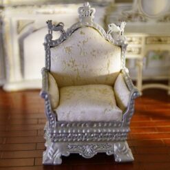 Miniature silver throne chair with intricate carvings and upholstery