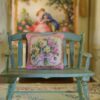 Miniature pillow with a bouquet of yellow and pink roses tied with a purple ribbon
