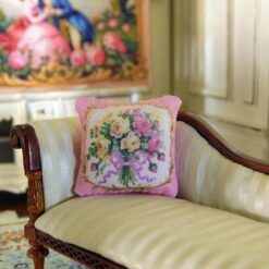 Miniature pillow with a bouquet of yellow and pink roses tied with a purple ribbon