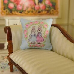 Miniature pillow design with two rabbits in blue and pink dresses surrounded by a rose wreath