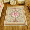 Miniature Rococo Victorian rug with scrolls, garlands, and central medallion.