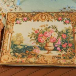 Miniature Aubusson tapestry featuring a golden urn with pastel roses framed by intricate scrollwork.