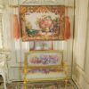 Miniature Aubusson tapestry featuring a golden urn with pastel roses framed by intricate scrollwork.