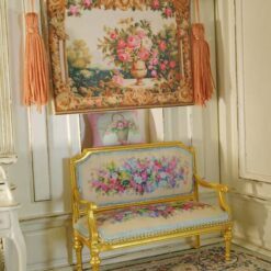 Miniature Aubusson tapestry featuring a golden urn with pastel roses framed by intricate scrollwork.
