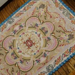 Miniature Aubusson rug with soft floral pattern and pastel borders.
