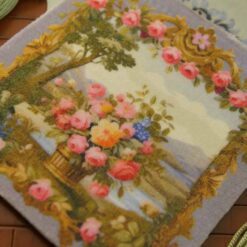 Basket filled with roses and wildflowers with a scenic backdrop in a miniature Aubusson tapestry.