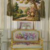 Countryside scene with golden urn, roses, and lush greenery in a miniature Aubusson tapestry.