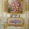 Lush floral arrangement in a golden urn surrounded by a garden scene and framed with gold, a miniature Aubusson tapestry.