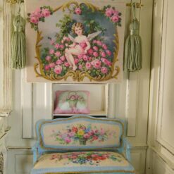 Winged cherub sitting among vibrant pink roses with golden details, a miniature Aubusson tapestry.