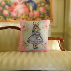 Miniature pillow featuring a bunny in a blue dress with pink roses