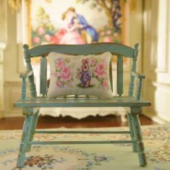 Miniature pillow with a rabbit in a blue jacket surrounded by pink roses