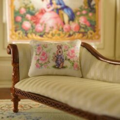 Miniature pillow with a rabbit in a blue jacket surrounded by pink roses