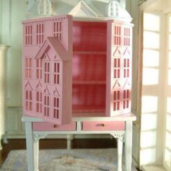Pink townhouse dollhouse on white table with drawers
