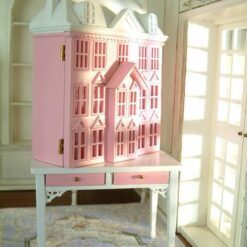 Pink townhouse dollhouse on white table with drawers