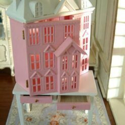 Pink townhouse dollhouse on white table with drawers