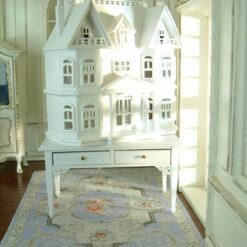 Victorian-style miniature dollhouse cabinet in white on a two-drawer table