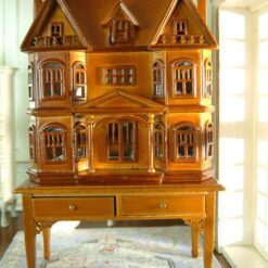 Victorian-style dollhouse cabinet in walnut finish with two-drawer table