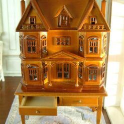Victorian-style dollhouse cabinet in walnut finish with two-drawer table