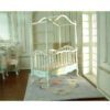Victorian-style dollhouse crib with white frame and turquoise hand-painted details
