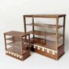 A vintage dollhouse bakery display cabinet with shelves and glass panels.